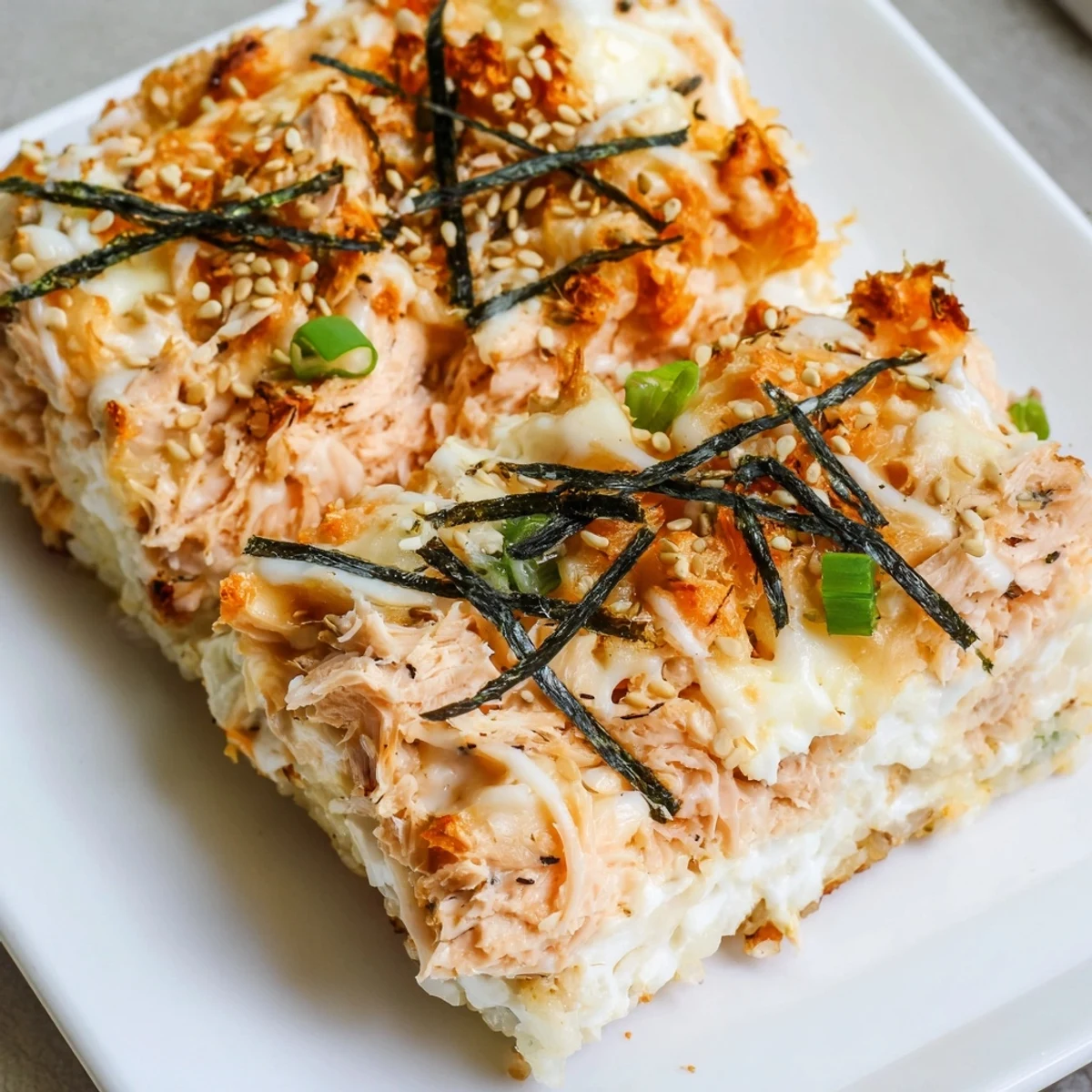 Golden, bubbling Creamy Salmon Sushi Bake, ready to scoop and enjoy with crispy nori sheets.