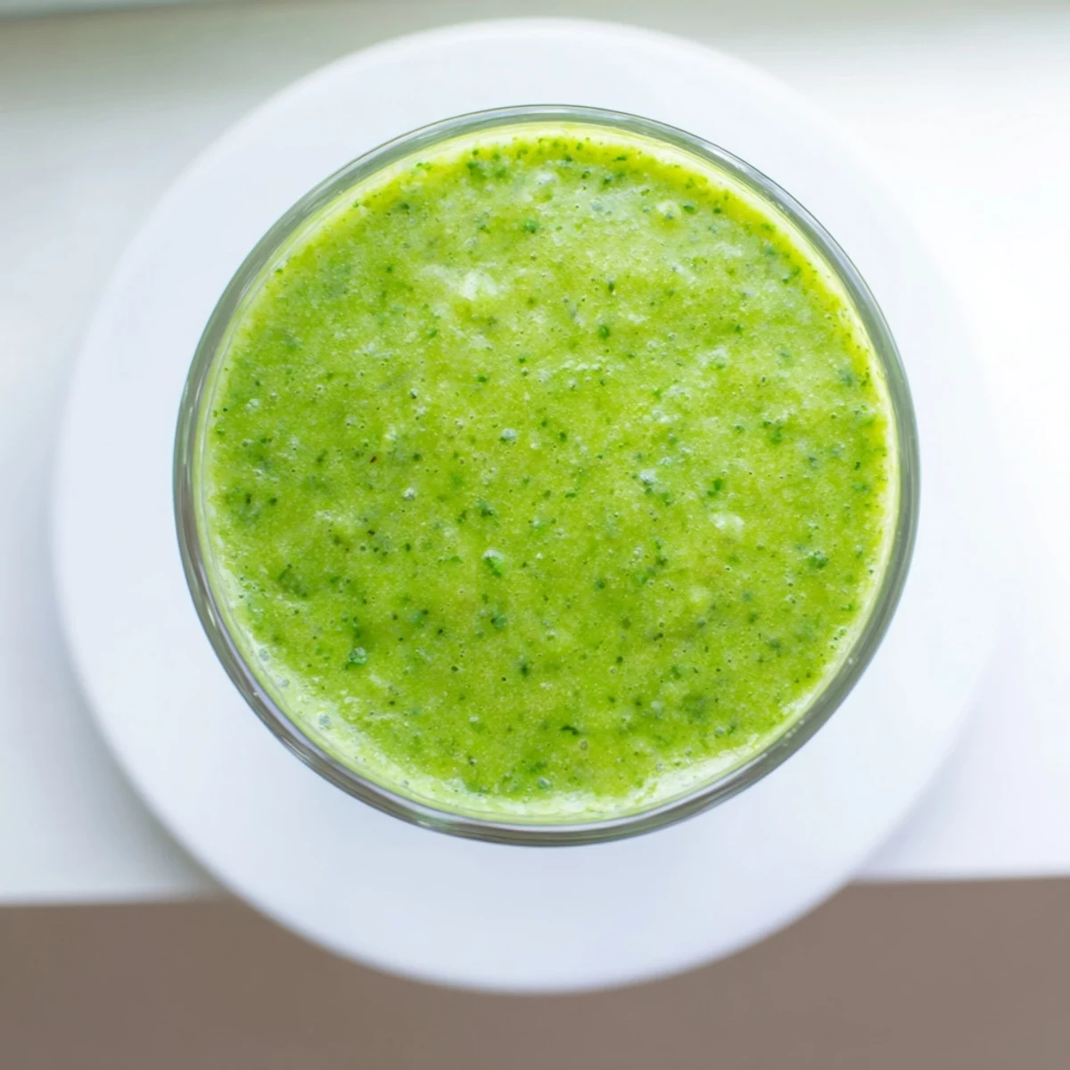 A thick and creamy Spinach-Hidden Smoothie, poured into a tall glass with a swirl of almond milk and chia seeds on top.