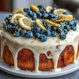 Vibrant lemon blueberry birthday cake with layers of moist lemon cake bursting with fresh blueberries, topped with silky lemon cream cheese frosting and edible flowers.