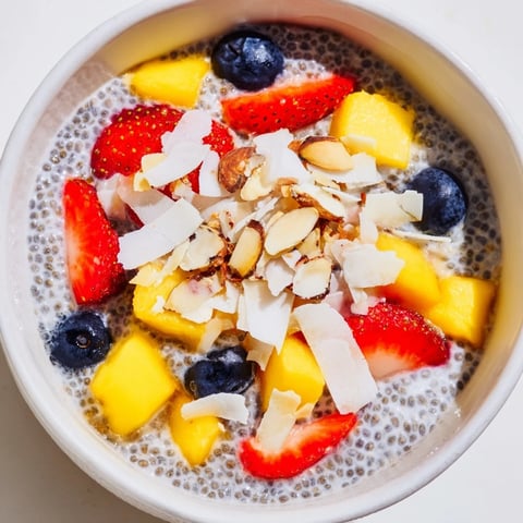 A jar of chilled chia seed pudding topped with fresh berries and a sprinkle of toasted coconut flakes.