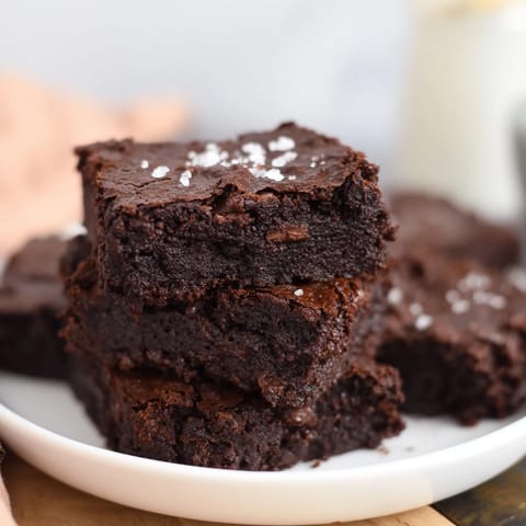 A square serving of Homemade Dark Chocolate and Sea Salt Brownies, ready to be enjoyed with vanilla ice cream.