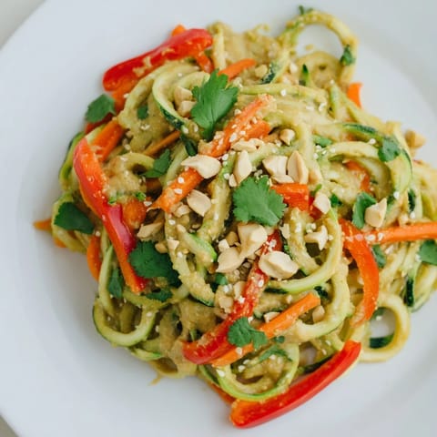Fresh Zesty Peanut Zucchini Noodles with chopped peanuts, cilantro, and bright red bell pepper ready to enjoy.