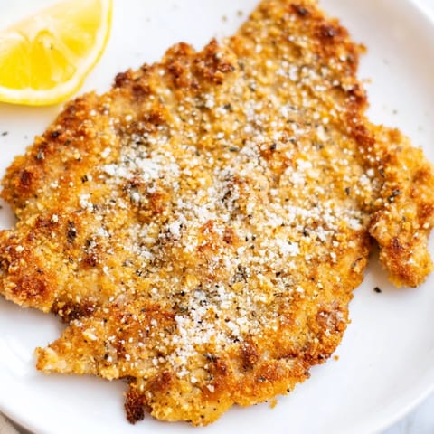 Crispy Parmesan Chicken Cutlet served on a rustic platter with a fresh arugula salad and lemon slices.