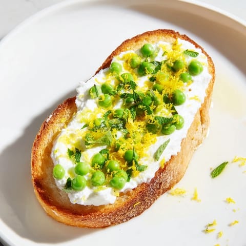 Fresh mint and lemon zest garnish this easy vegetarian toast, topped with a creamy spread made from sweet peas and ricotta.