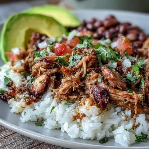 A finished Carnitas Bowl loaded with tender shredded pork, fresh avocado slices, and zesty salsa.