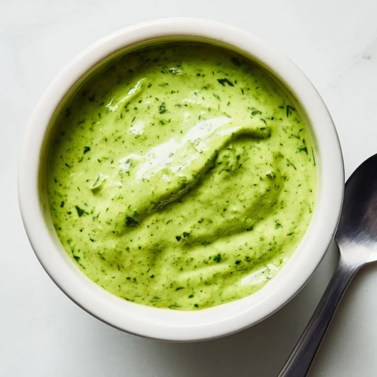 A creamy bowl of Green Goddess Dressing garnished with chopped herbs, served as a dip.  