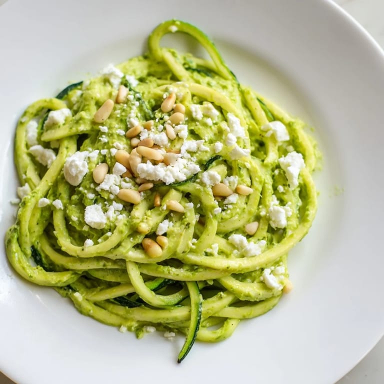 Sautéed zucchini noodles served in a bowl with cherry tomatoes and crumbled feta, showcasing a quick, low-carb pasta alternative.