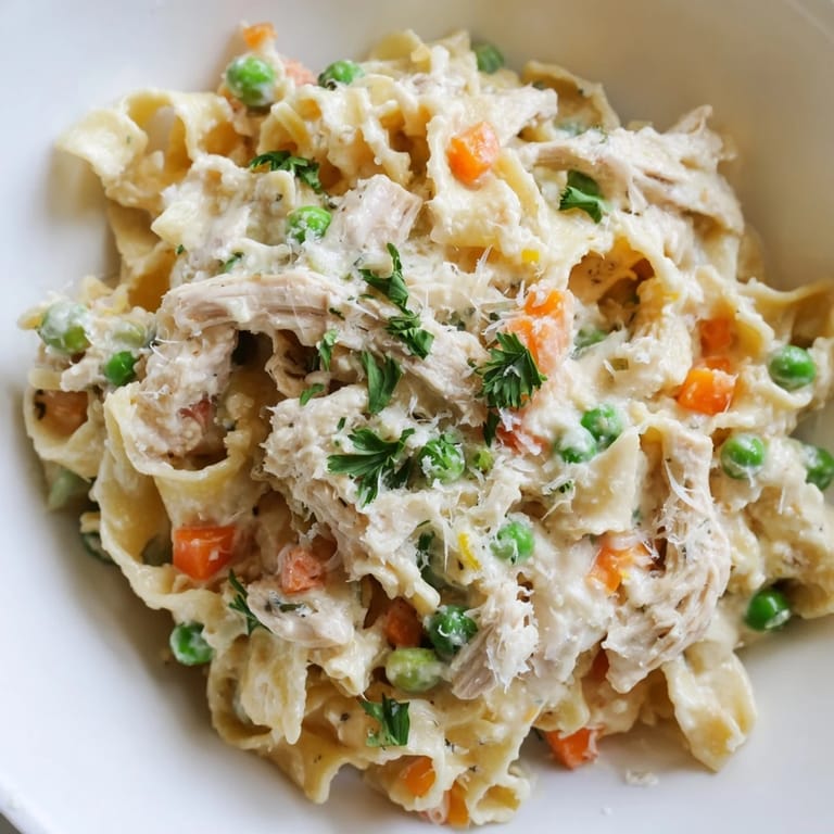 Spring Chicken Noodle Skillet in a warm ceramic bowl, featuring shredded chicken, egg noodles, peas, and carrots, perfect for a comforting family dinner.