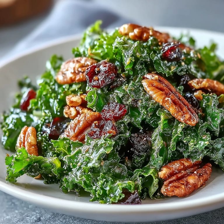 A vibrant bowl of Warm Kale Salad With Maple Mustard Dressing garnished with crumbled feta and sweet dried cranberries for a comforting side.