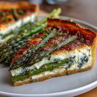 Spring Asparagus Tart with Puff Pastry, golden and flaky, topped with vibrant green asparagus spears, creamy cheese, and fresh herbs.